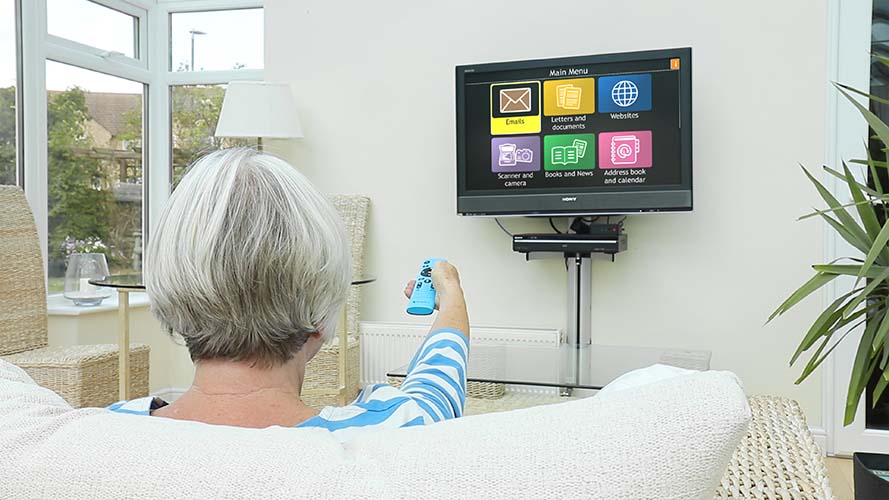 Senior woman pointing a Dolphin Remote at GuideConnect display on a TV
